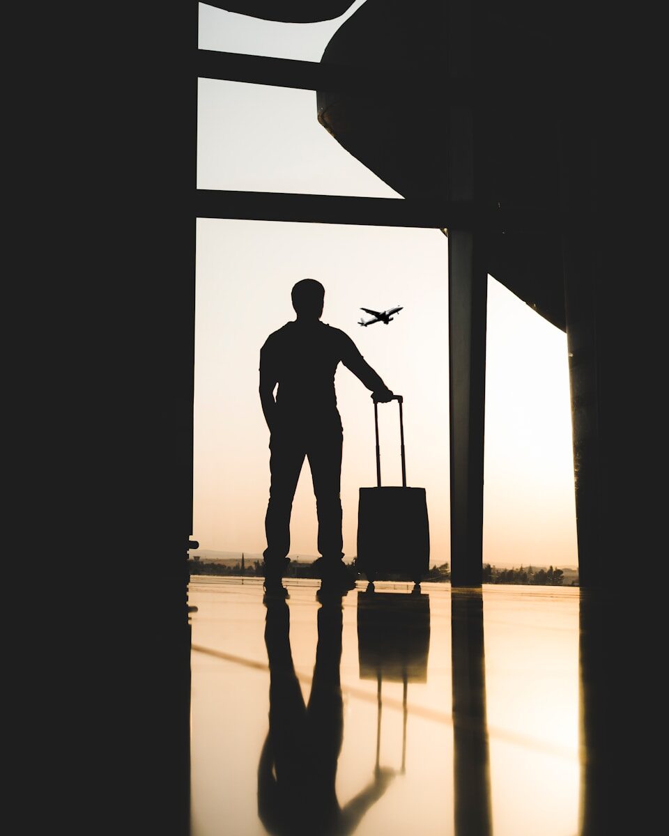 Photo by yousef alfuhigi silhouette of man holding luggage inside airport
